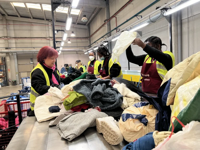 Un grupo de personas categorizando ropa en el proyecto Moda RE de Cáritas